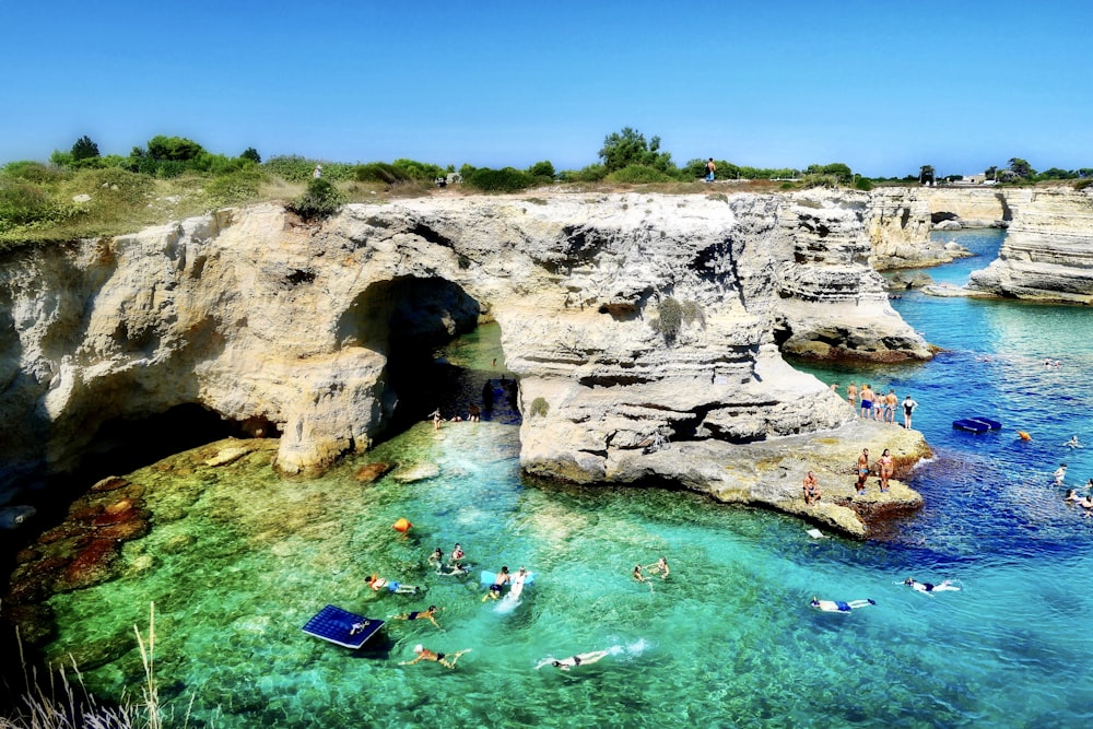 persone che nuotano sullo specchio d'acqua blu durante il giorno