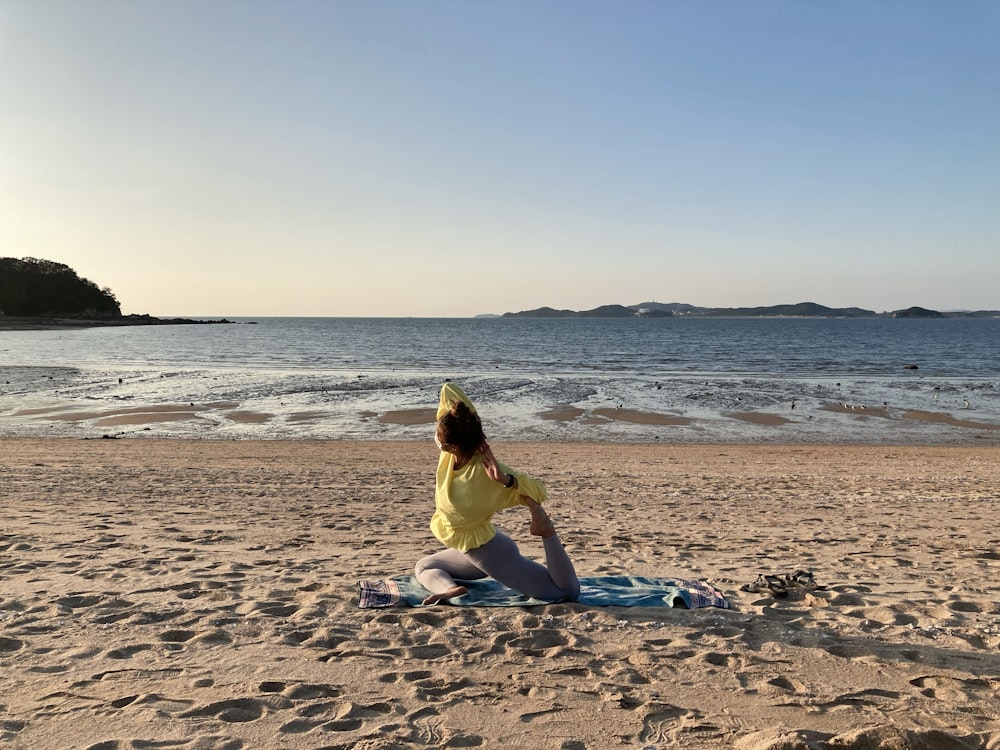 woman in yellow dress sitting on beach shore during daytime