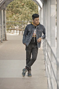 A stylish young man in casual streetwear leaning against a city wall, showcasing modern men's fashion.