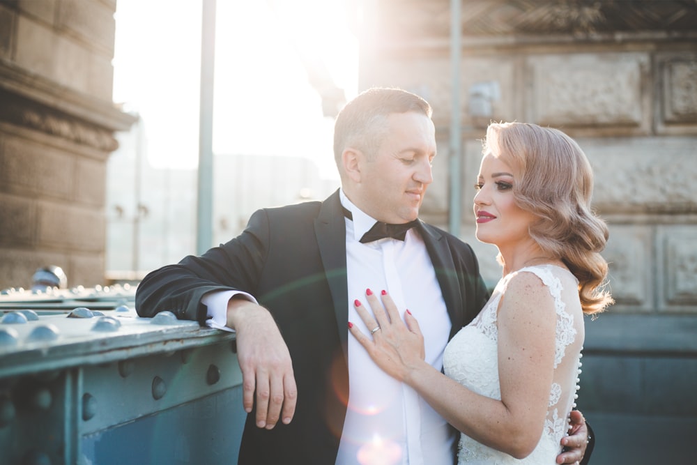 man in black suit jacket kissing woman in white sleeveless dress