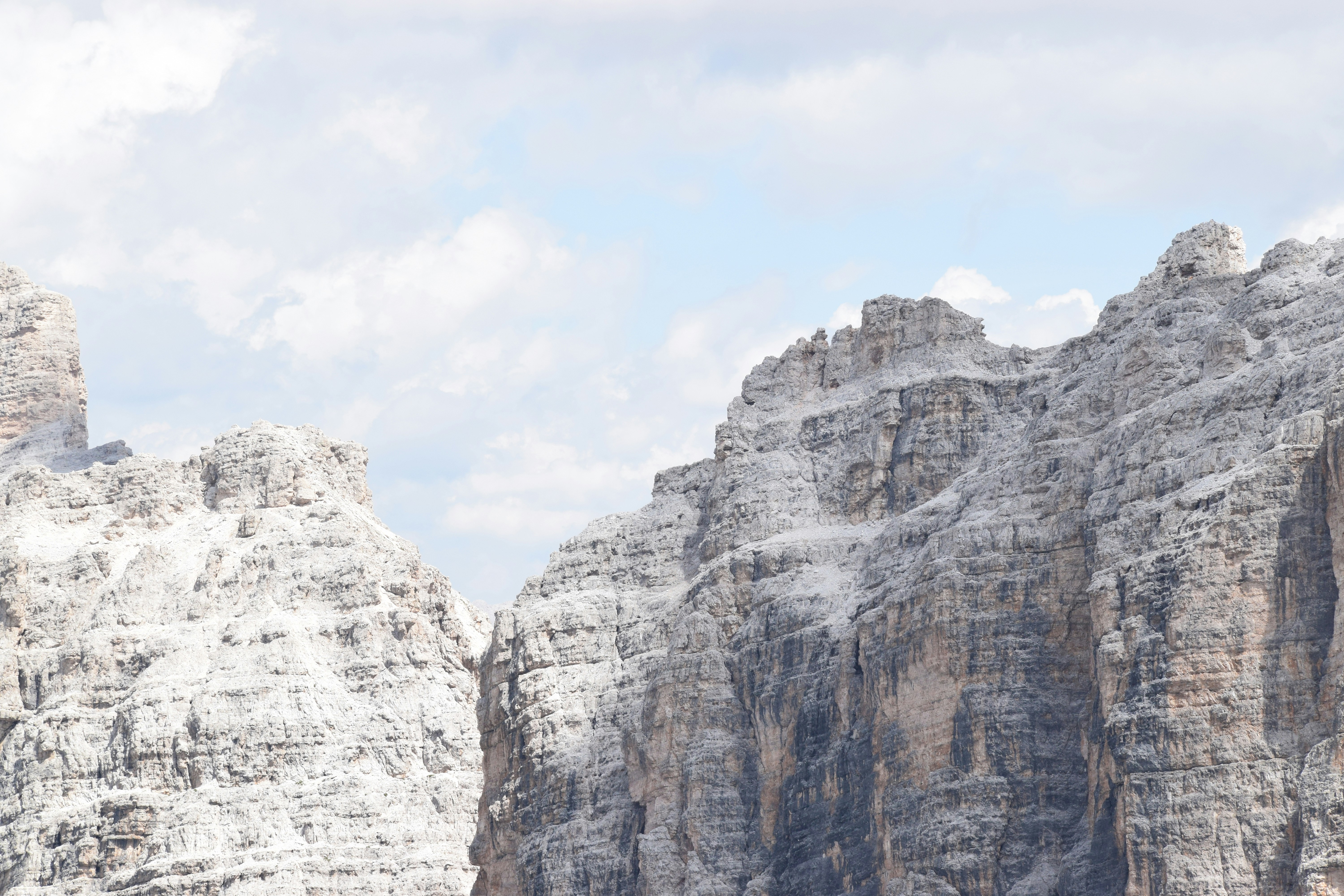 昼間の白い空の下の灰色の岩山の写真 Unsplashで見つけるイタリア語の無料写真