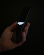 A hand holding a smartphone displaying the word 'CHEF' with a stylized knife logo on a dark screen. The background is dark, emphasizing the glow from the screen.