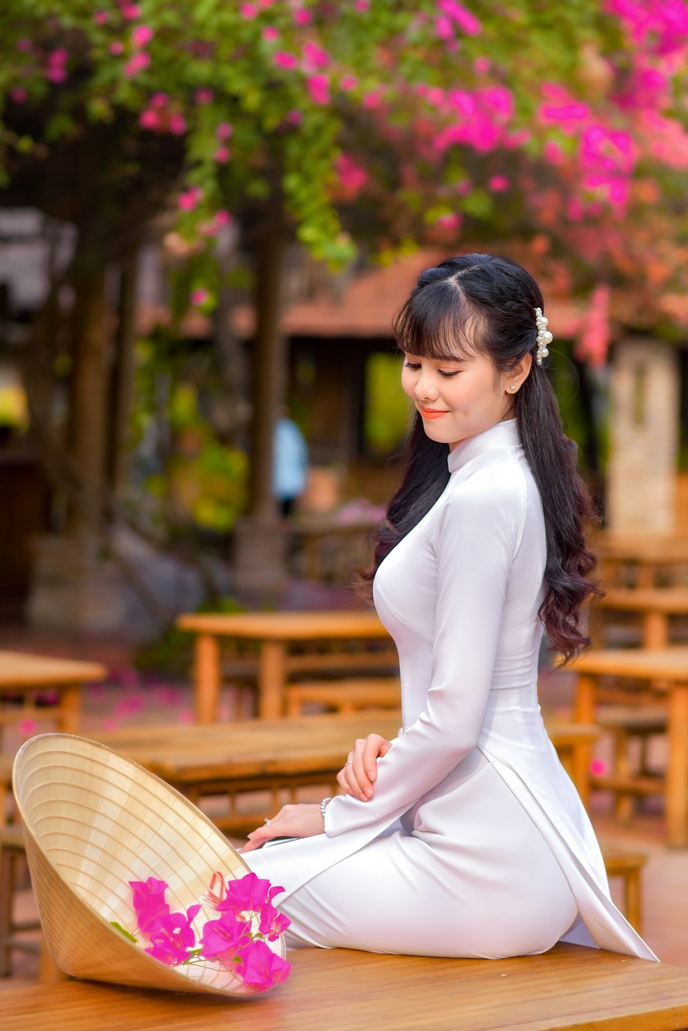 Mujer en vestido blanco de manga larga sentada en banco de madera marrón durante el día