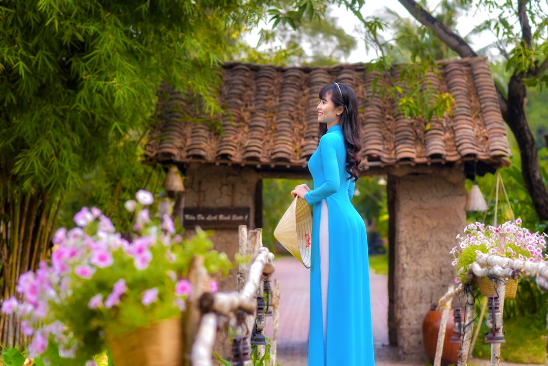 woman in blue dress standing near brown concrete building during daytime