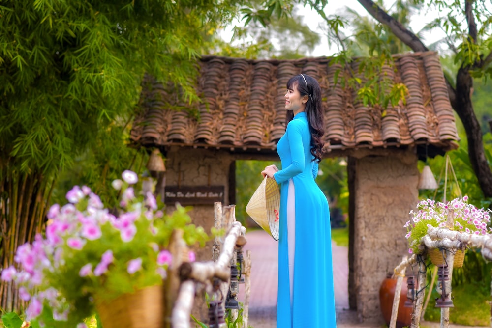 woman in blue dress standing near brown concrete building during daytime