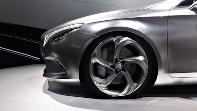 A sleek, modern car with an emphasis on its stylized front wheel and smooth metallic body. The car's design is aerodynamic, with a prominent headlight and a flowing contour.