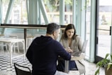 man in black long sleeve shirt sitting on chair beside woman in black and white stripe