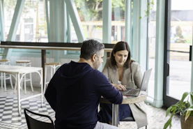 A man and a woman working on a laptop at a cafe table