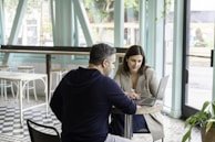 man in black long sleeve shirt sitting on chair beside woman in black and white stripe