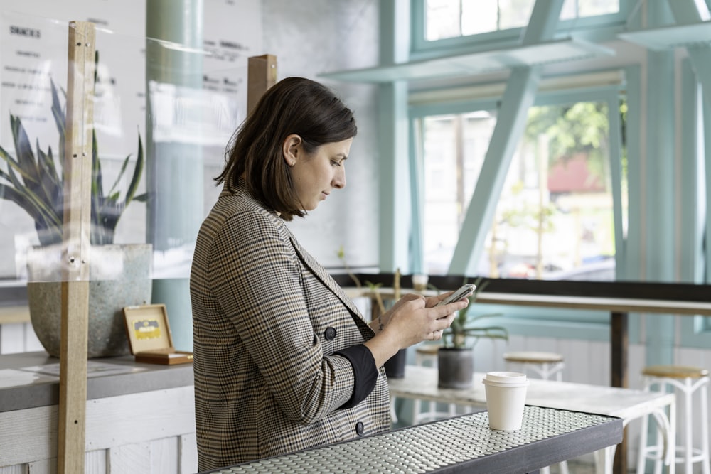 woman in black and white checkered long sleeve shirt using smartphone