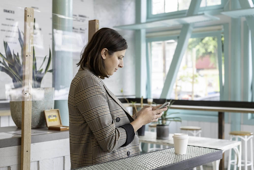 Mujer en camisa de manga larga a cuadros en blanco y negro usando teléfono inteligente