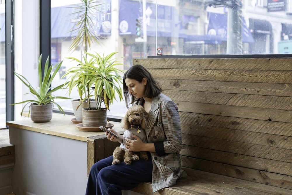 woman in gray sweater carrying brown dog