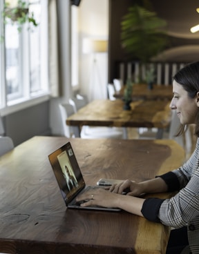 woman in gray and white striped long sleeve shirt using silver macbook