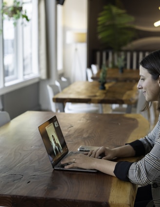 woman in gray and white striped long sleeve shirt using silver macbook