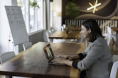 woman in gray and white striped long sleeve shirt using silver macbook
