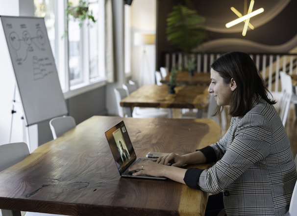 woman in gray and white striped long sleeve shirt using silver macbook