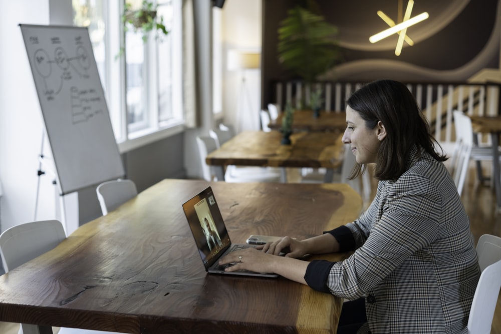 シルバーのMacBookを使用したグレーと白のストライプの長袖シャツの女性