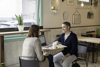 man in black sweater sitting beside woman in white and black striped long sleeve shirt