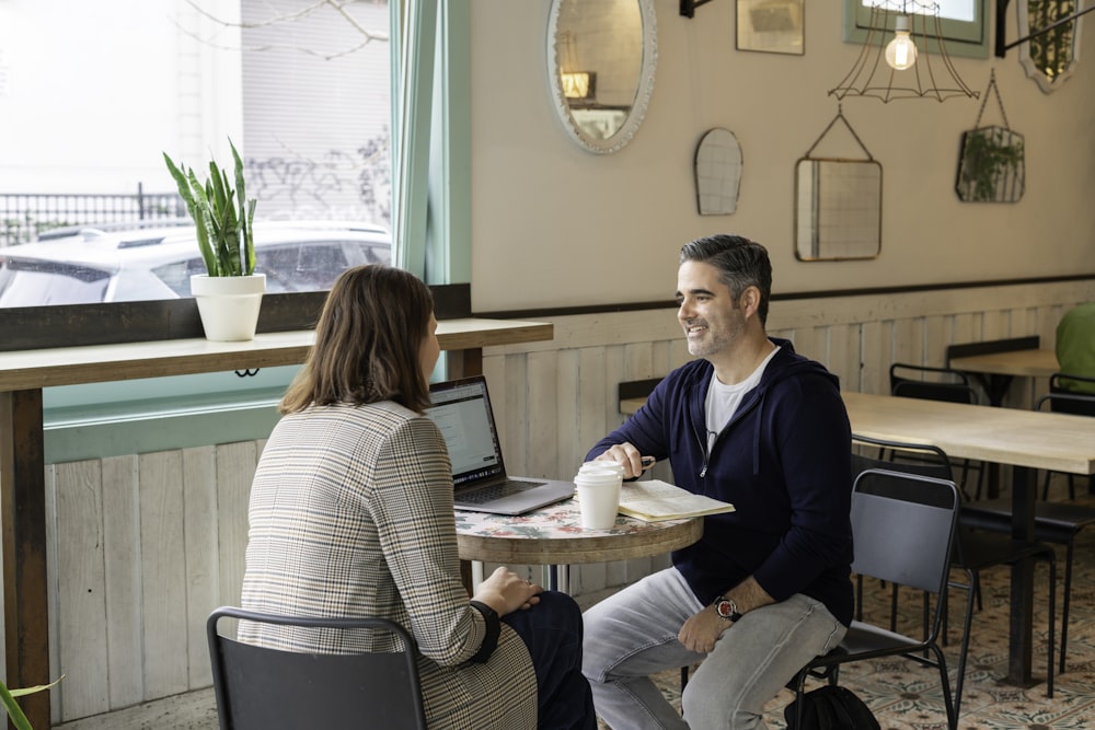 man in black sweater sitting beside woman in white and black striped long sleeve shirt