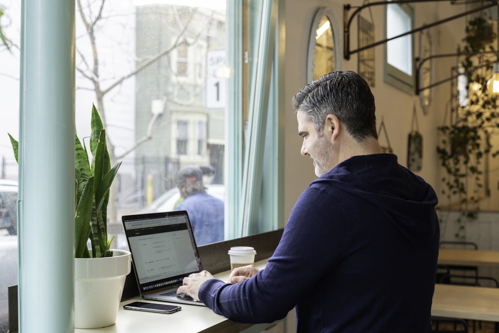 man in blue long sleeve shirt using macbook pro