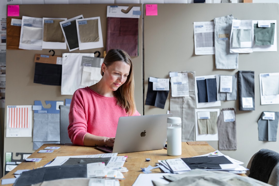 woman in red long sleeve shirt sitting in front of silver macbook, A businesswoman working in an office