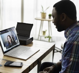 man in blue and white plaid dress shirt using macbook pro