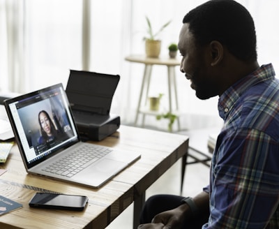 man in blue and white plaid dress shirt using macbook pro