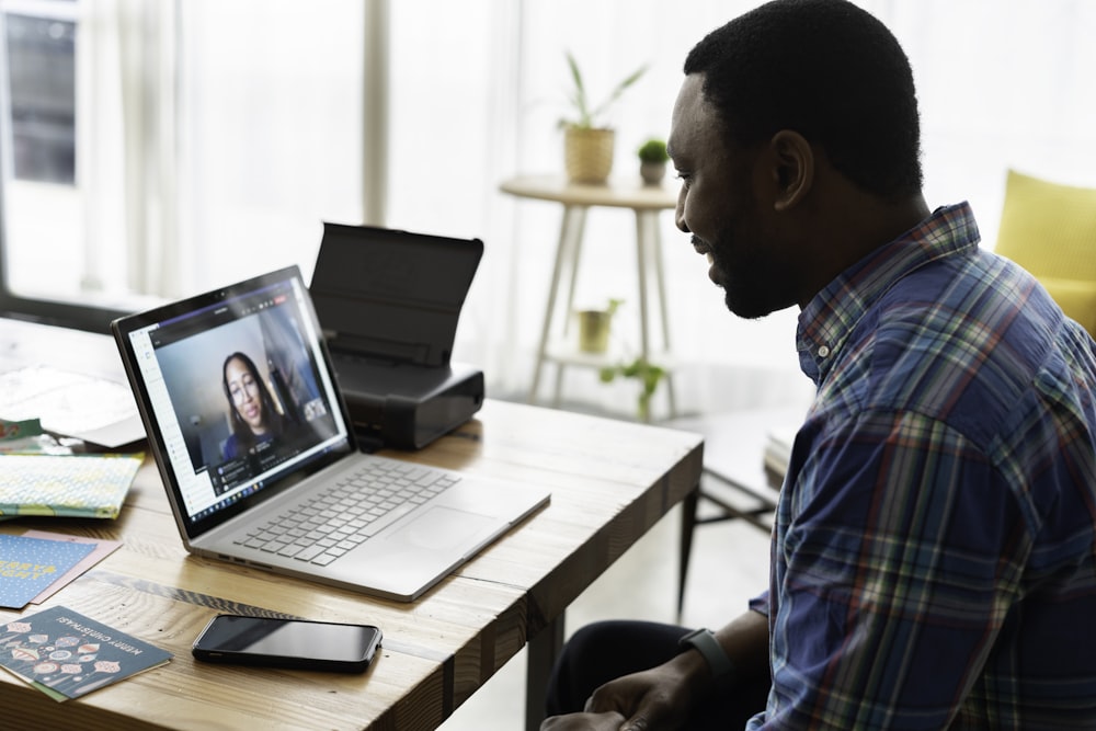 homem na camisa social xadrez azul e branca usando macbook pro