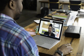 man in blue and white plaid shirt using macbook pro