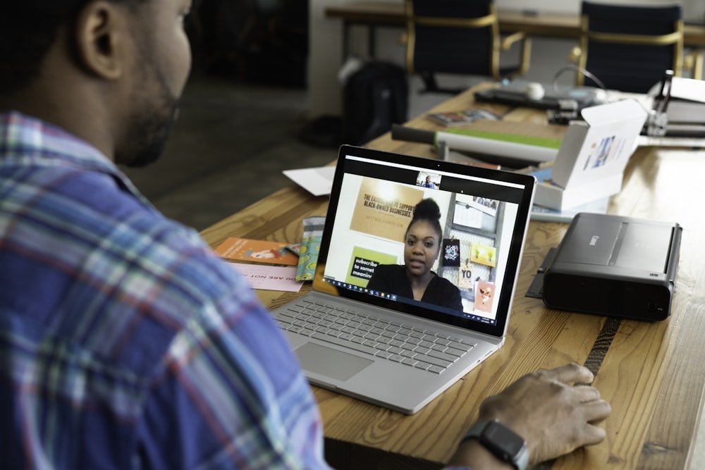 man in blue and white plaid shirt using macbook pro