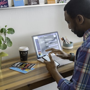 man in blue and red plaid dress shirt using silver ipad