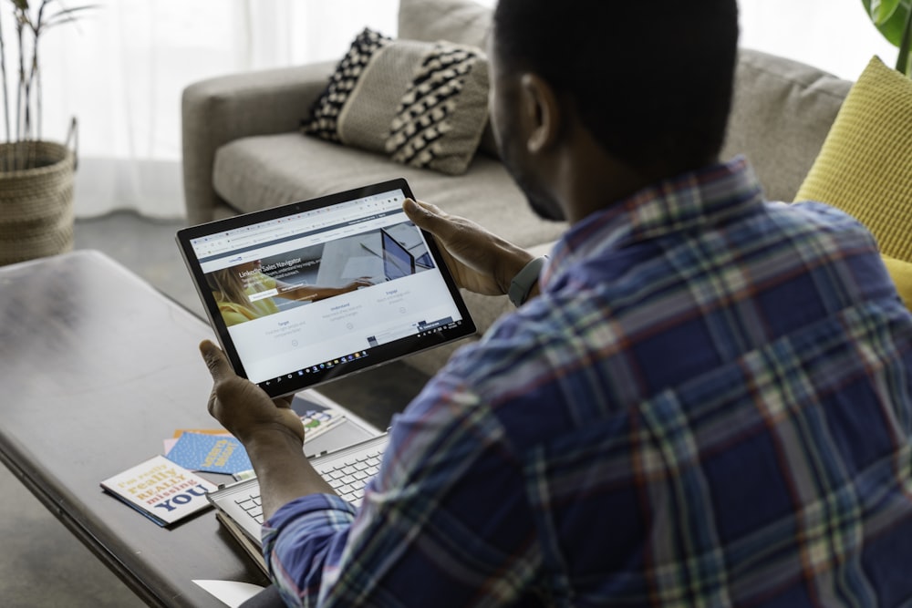 Homme en chemise à carreaux bleu, blanc et rouge utilisant un MacBook Pro