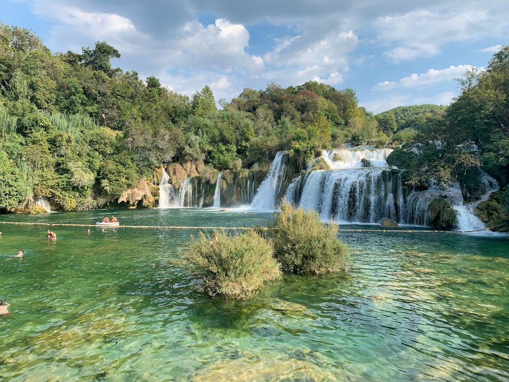 people in water falls during daytime