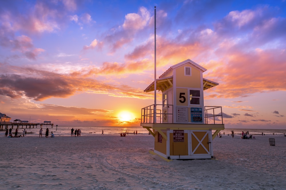 Weißes hölzernes Rettungsschwimmerhaus am Strand während des Sonnenuntergangs