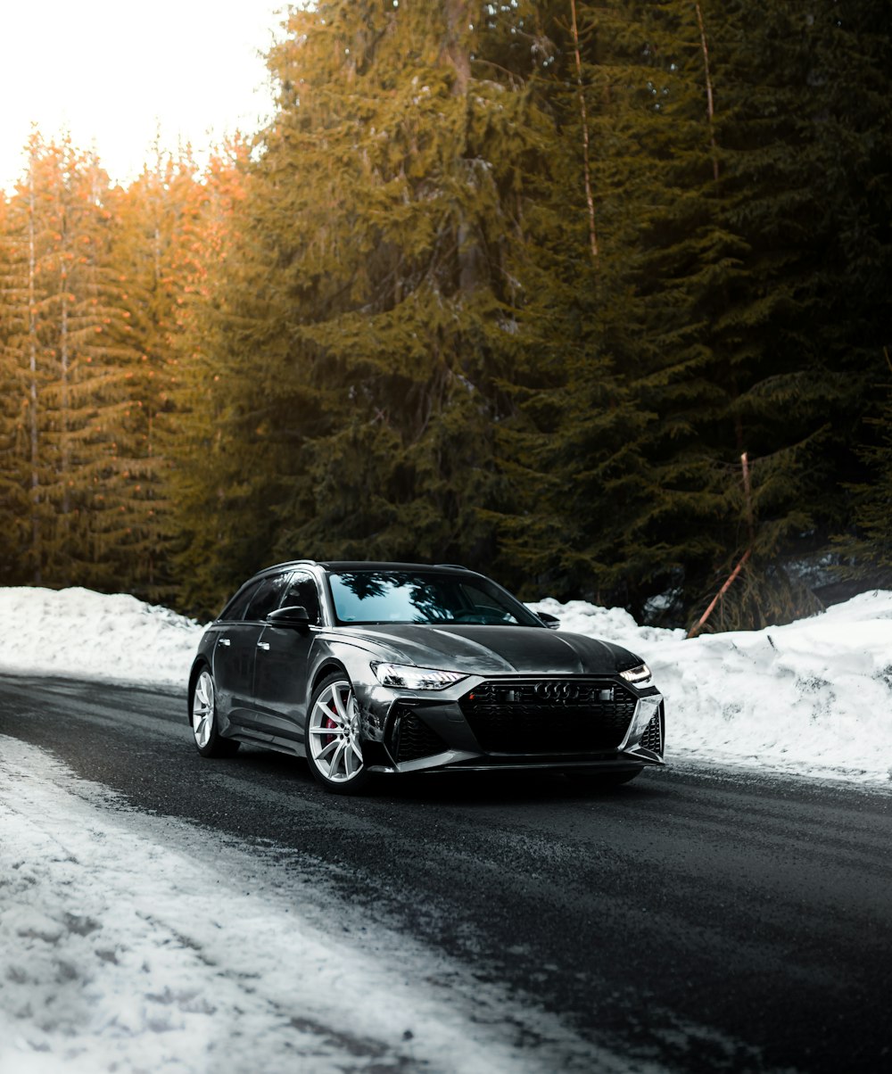 Porsche 911 preto na estrada coberta de neve durante o dia