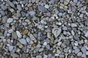 Pebbles on a beach. One pebble has a question mark drawn on it.