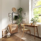 A peaceful corner of a single room with a small desk and window letting in natural light.