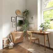 A calm, sunlit office corner featuring a wooden desk and a small potted plant.