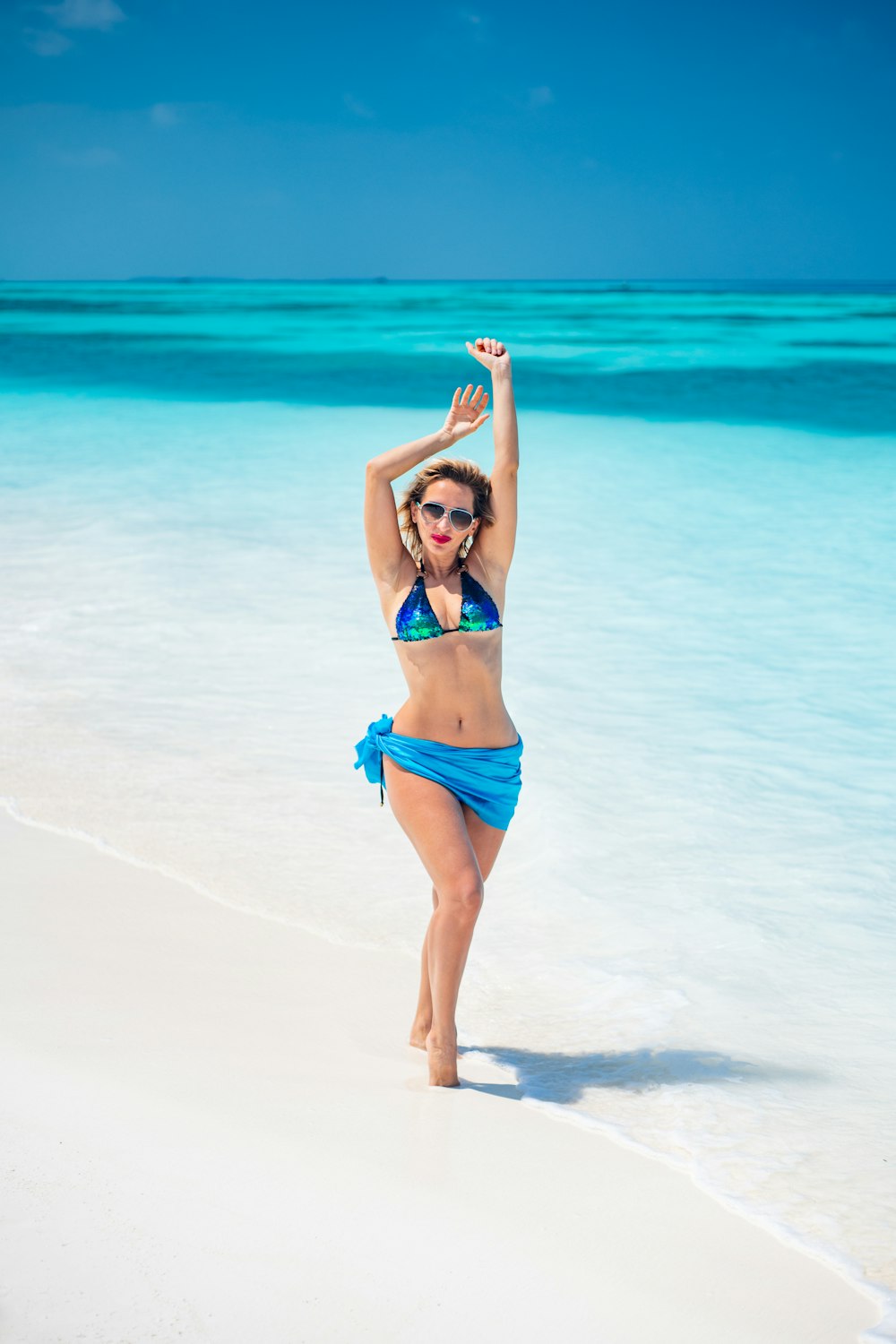 mulher no biquíni azul em pé na praia durante o dia