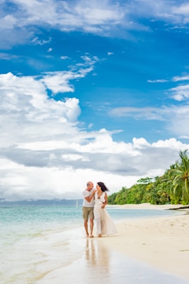 man and woman standing on beach during daytime