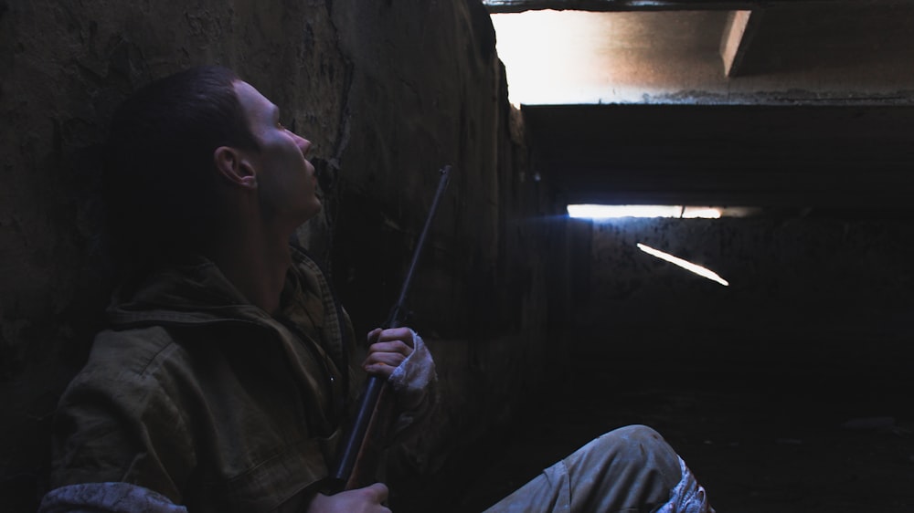 man in brown jacket holding stick