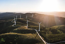 A panoramic view of a solar farm stretching across rolling hills at sunset.