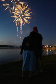 A serene moment of a couple watching fireworks together, wrapped in a cozy embrace.