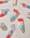 A playful arrangement of colorful popsicles, cupcakes, and two tubes of a product labeled 'not pot' displayed on a surface sprinkled with glitter and star-shaped confetti, creating a whimsical and festive atmosphere.
