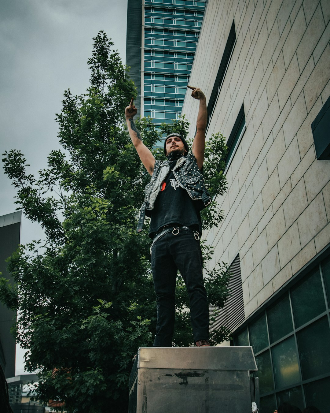 man in black and white t-shirt and black pants standing on gray concrete building during