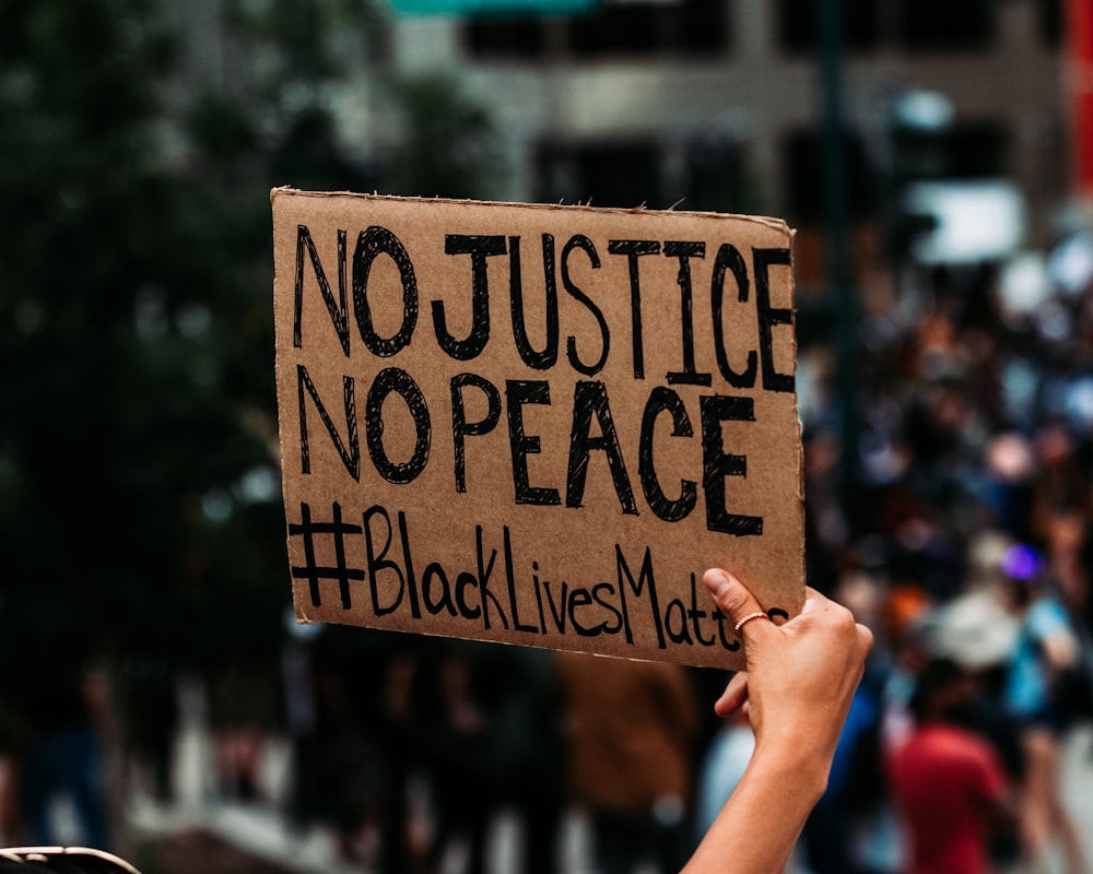 a person holding a sign that says no justice no peace