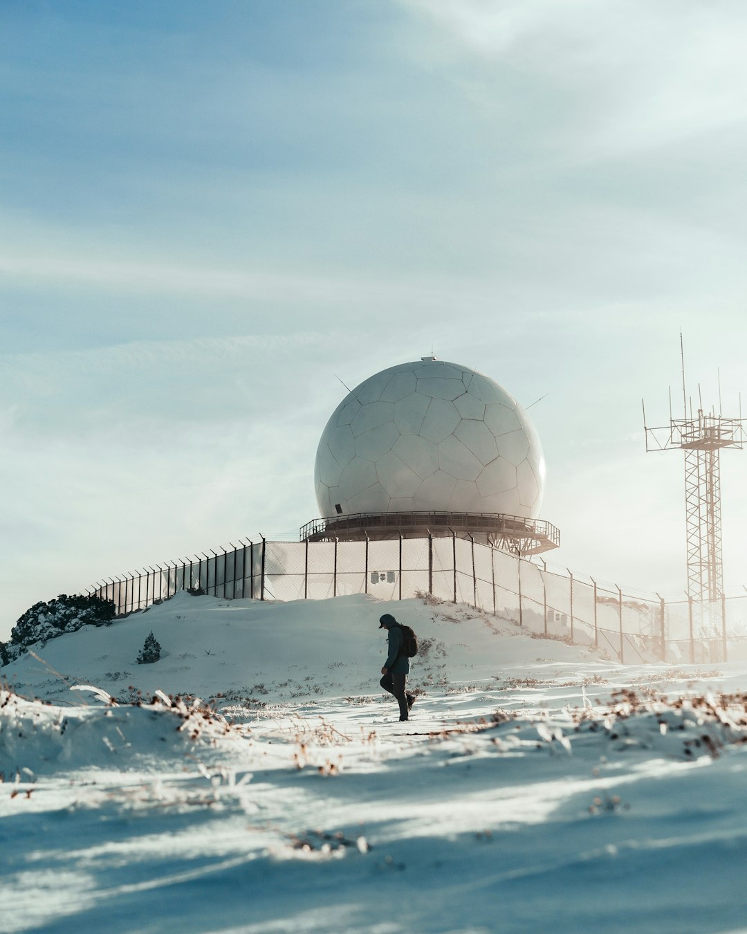 man in black jacket and black pants standing on snow covered ground near dome building during