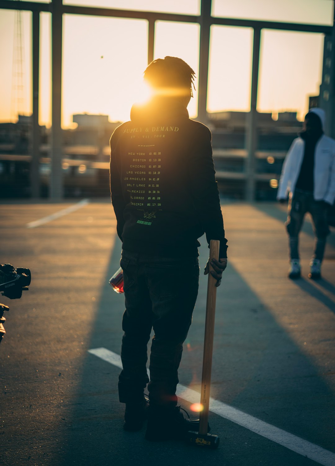 man in black jacket and blue denim jeans standing on sidewalk during night time