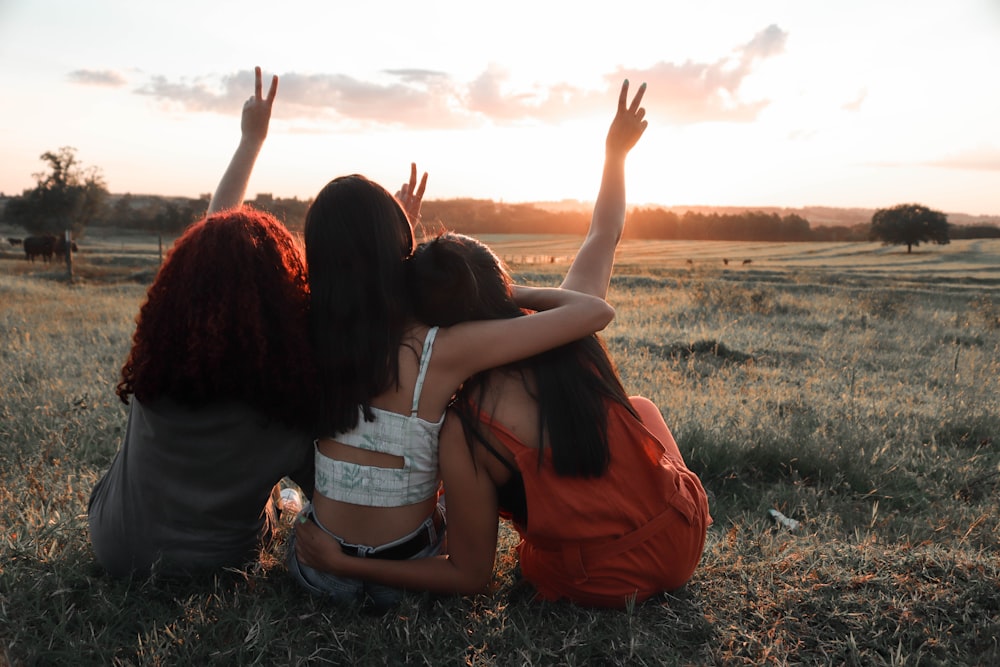 2 mulheres sentadas no campo de grama durante o dia