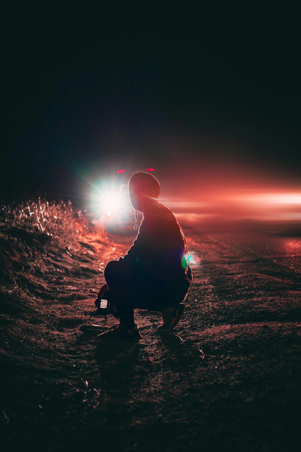 man in black jacket sitting on ground during sunset